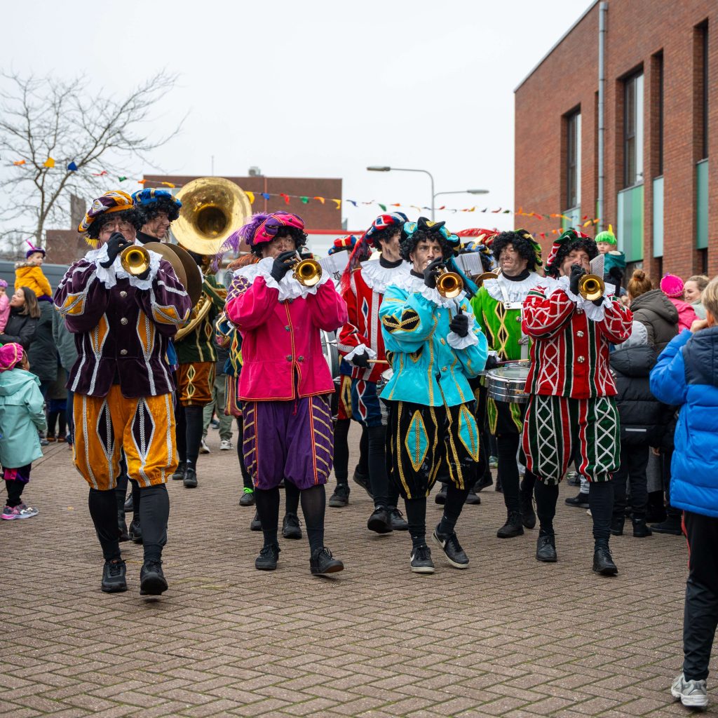 Optocht met muzikanten in kleurrijke kostuums tijdens Sinterklaas intocht.
