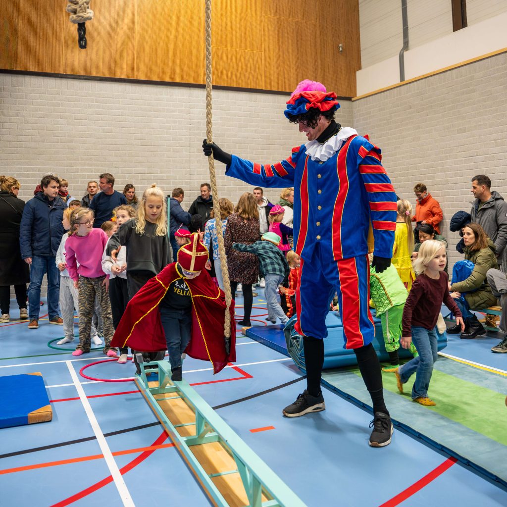 Sinterklaas intocht met kinderen en Pieten in sporthal.
